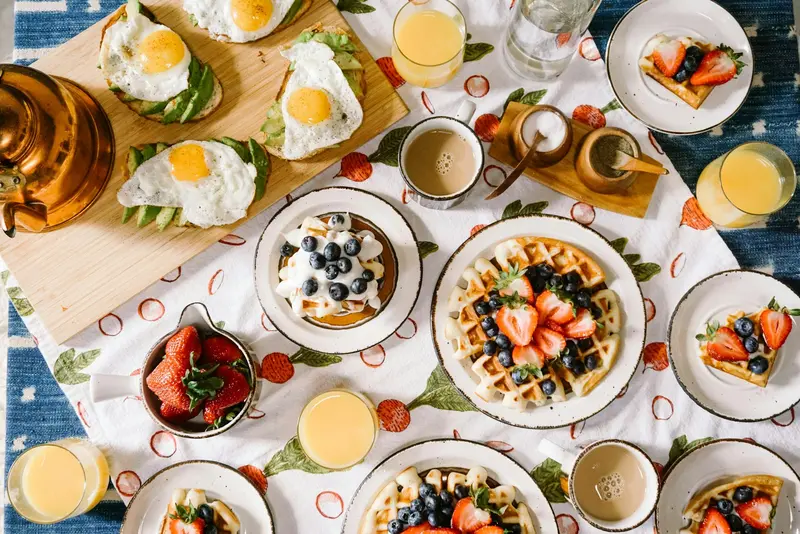 Mesa de desayuno con waffles, frutas y jugo